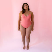 A coral colored spaghetti strap one piece swimsuit. 