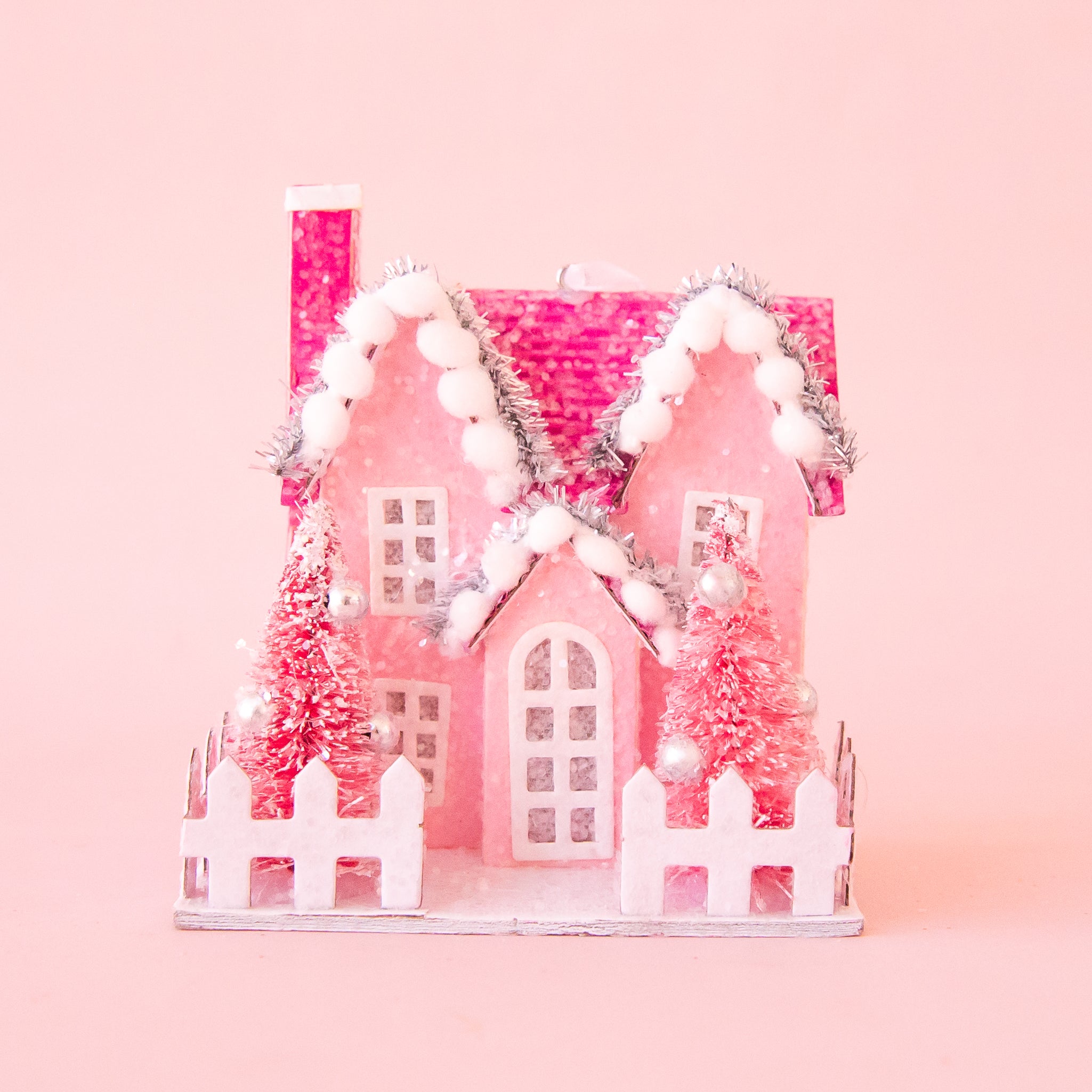 A pink holiday themed house shaped ornament. 