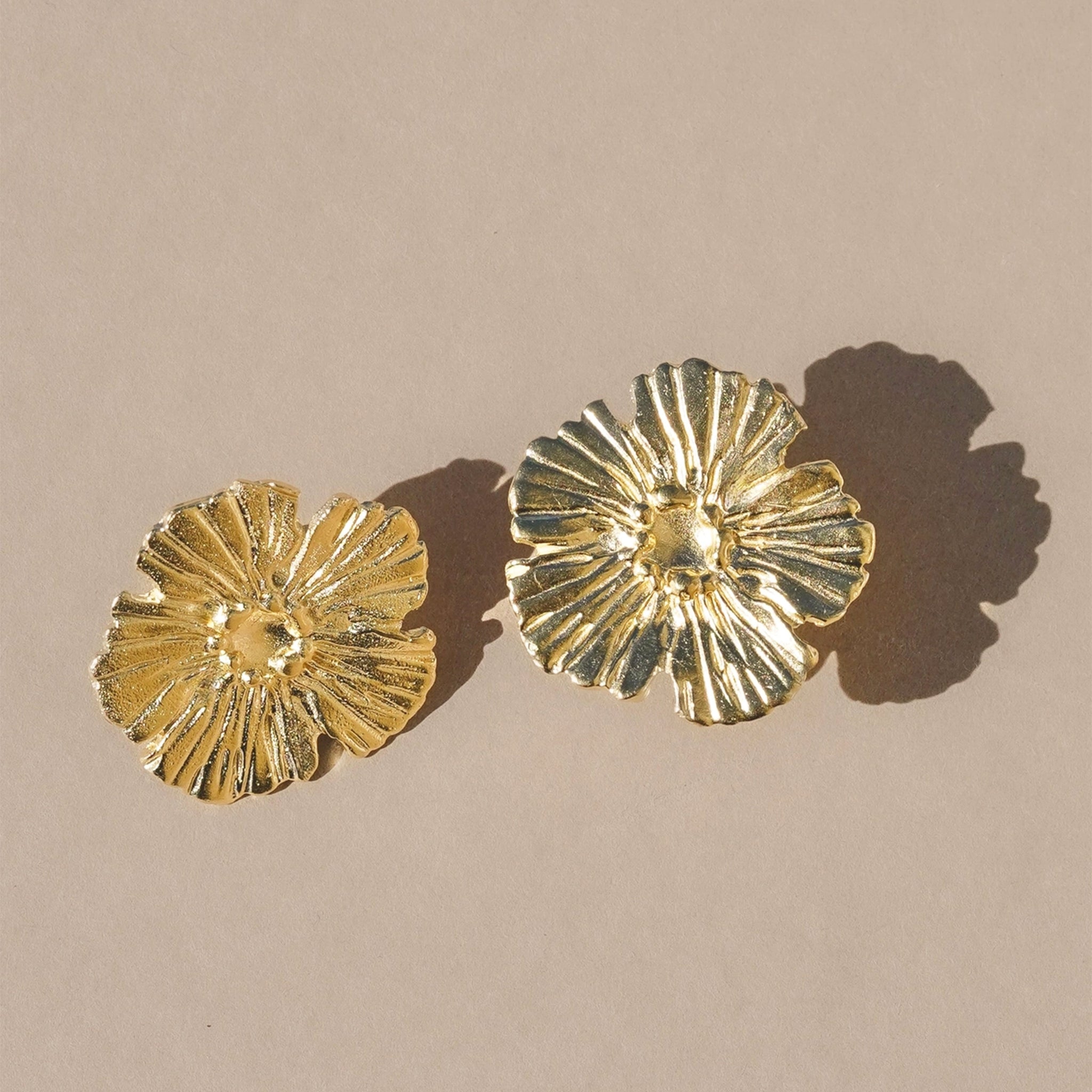 A gold pair of flower shaped earrings. 