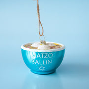 A glass matzo ball soup ornament with dumplings and a blue bowl that says "matzo ballin" in white text.