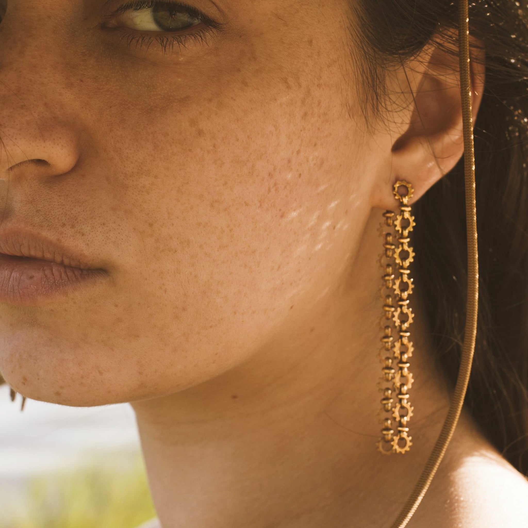 A pair of dangle chain earrings that have a sun shaped chain link. 