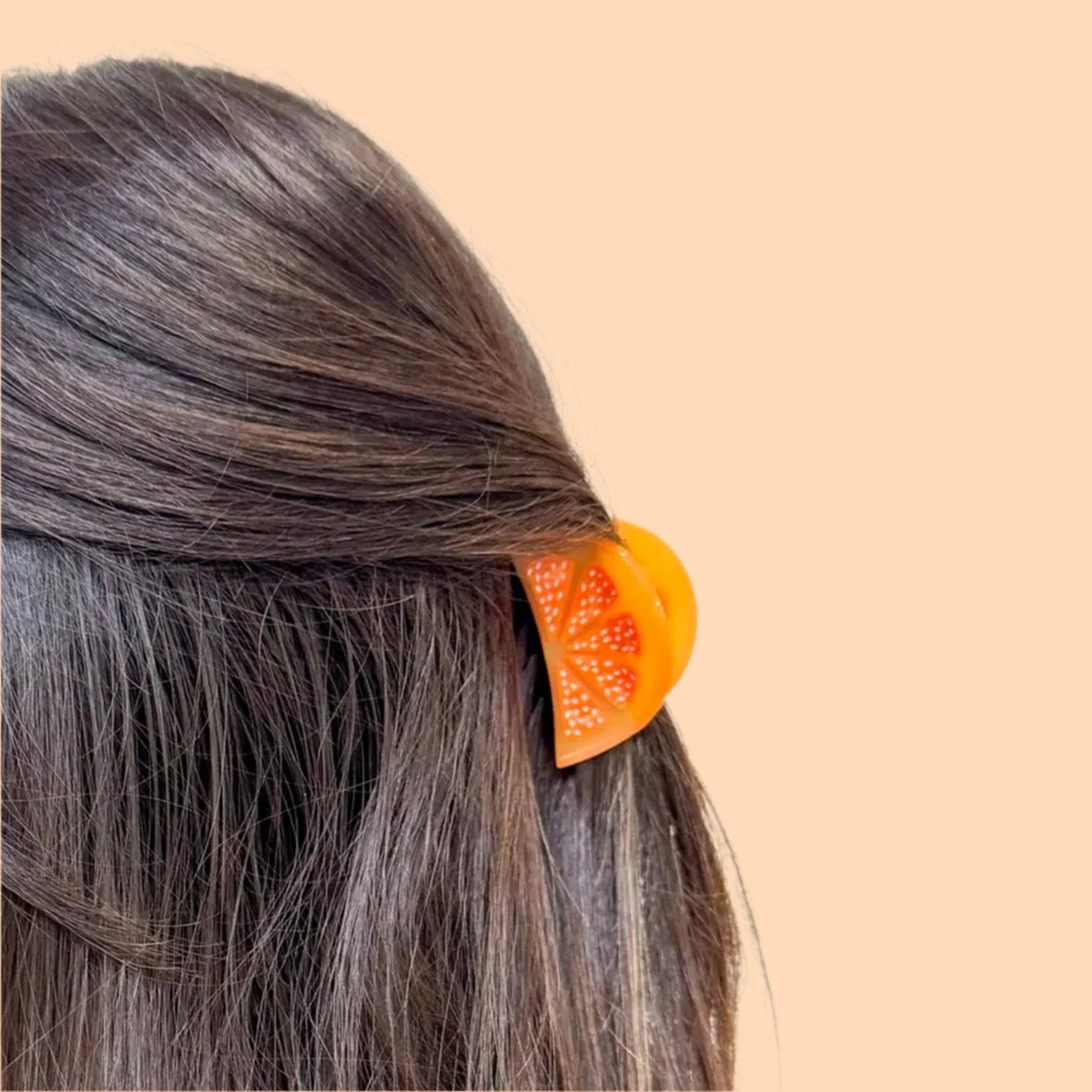 A mini orange slice shaped hair claw clip. 