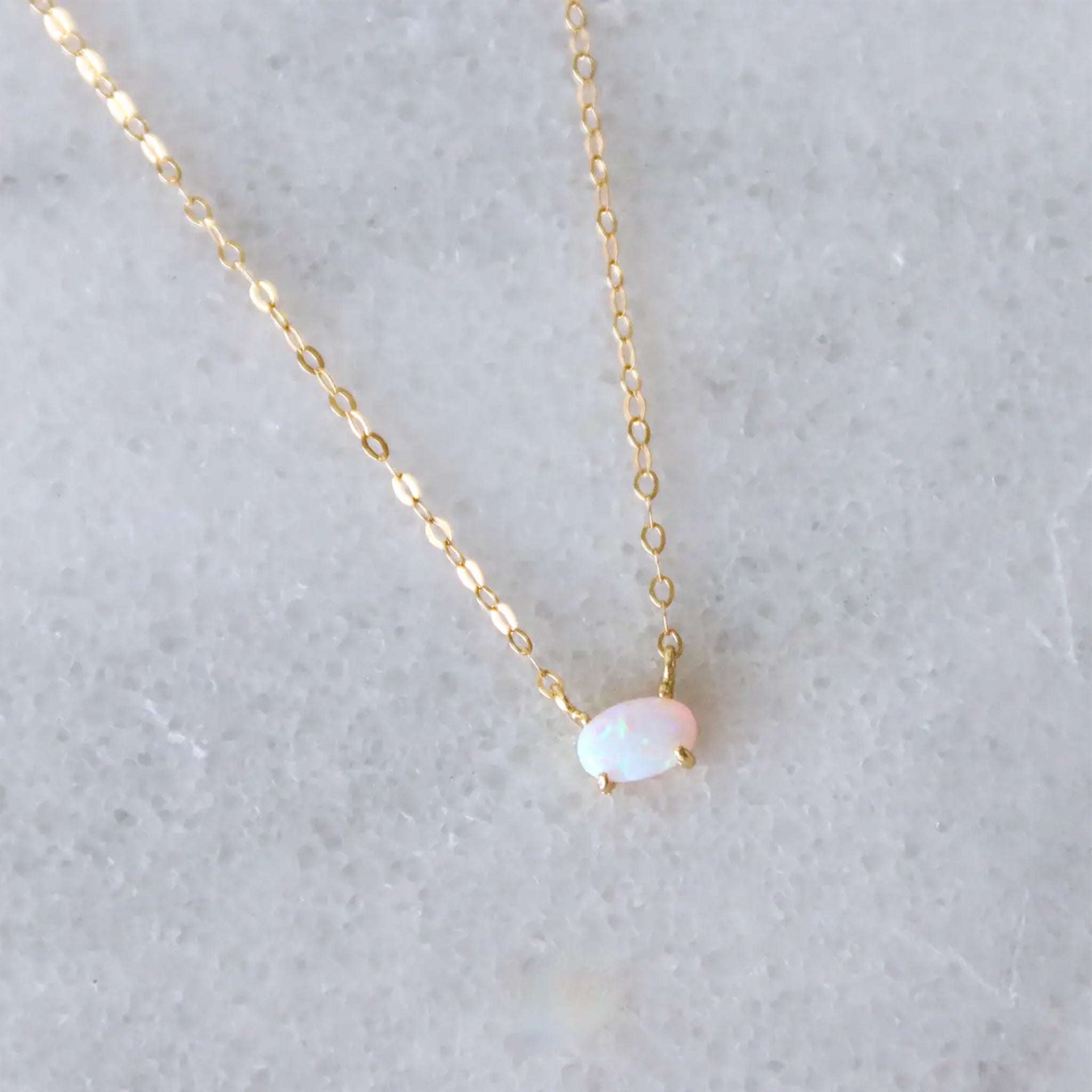 A gold necklace with an oval opal stone in the center. 