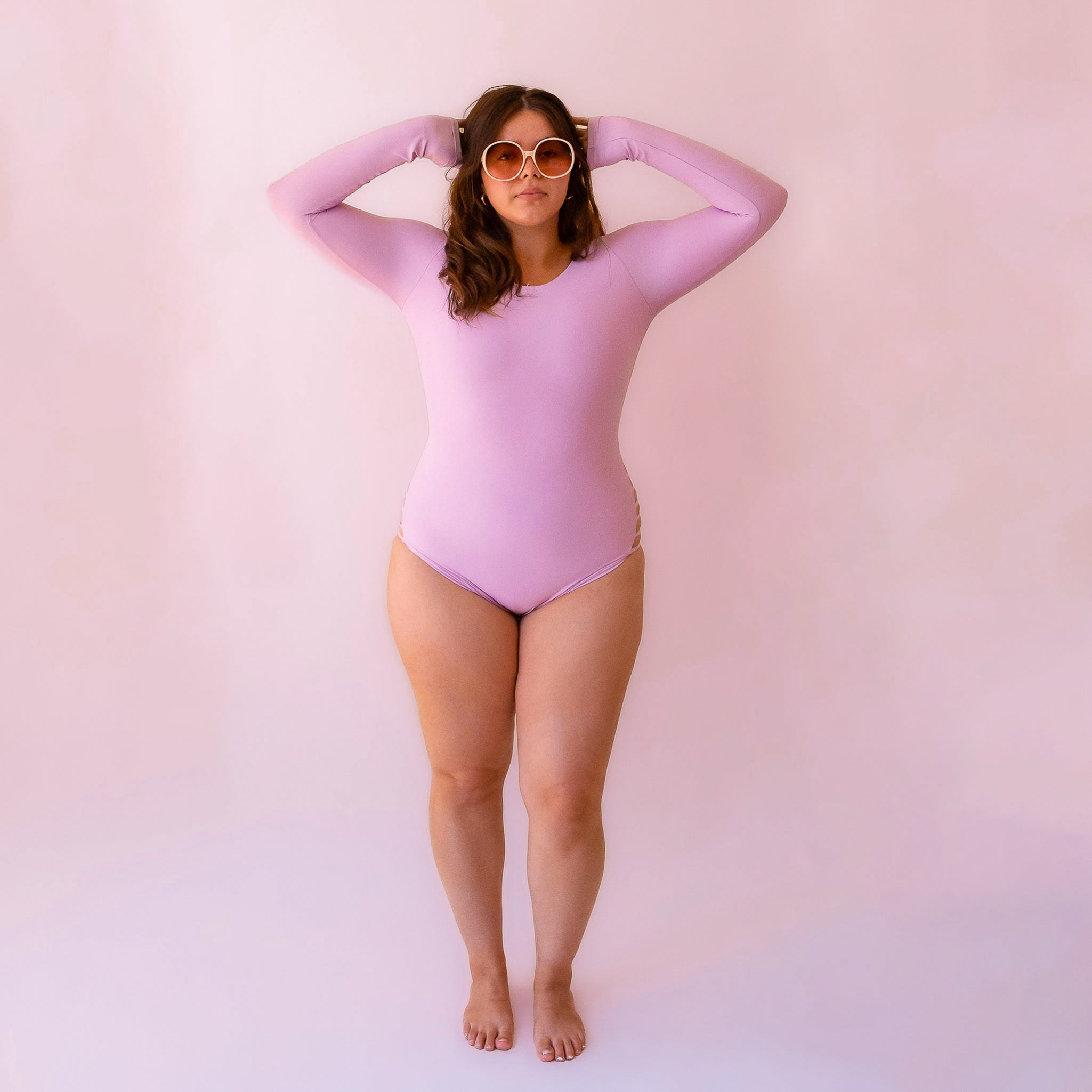 A model wearing a lilac purple long sleeve surf swimsuit. 