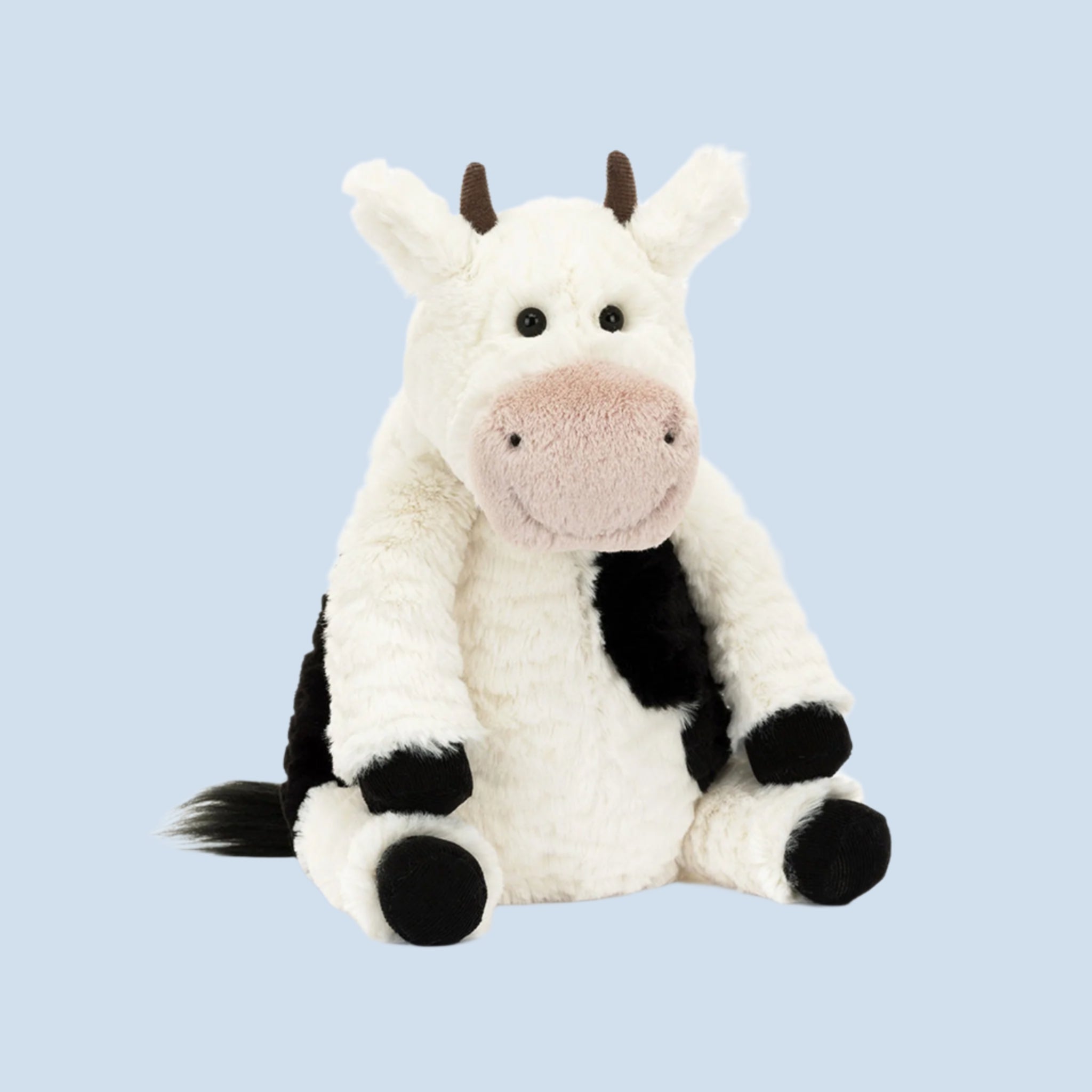 A cow shaped stuffed animal with a smiling face. 