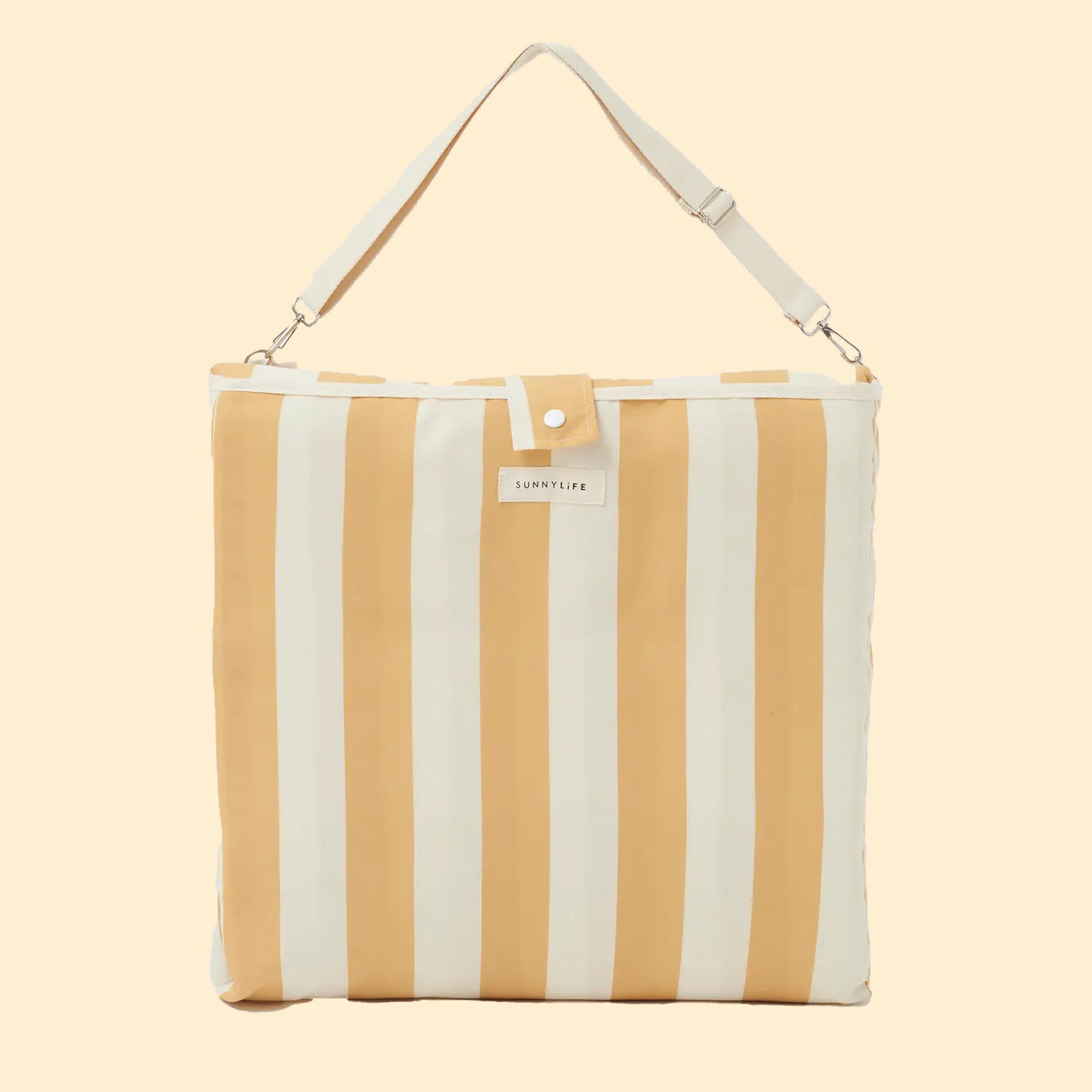 A mustard and ivory striped unfoldable beach or pool chair with folds into a compact square with a strap for carrying.