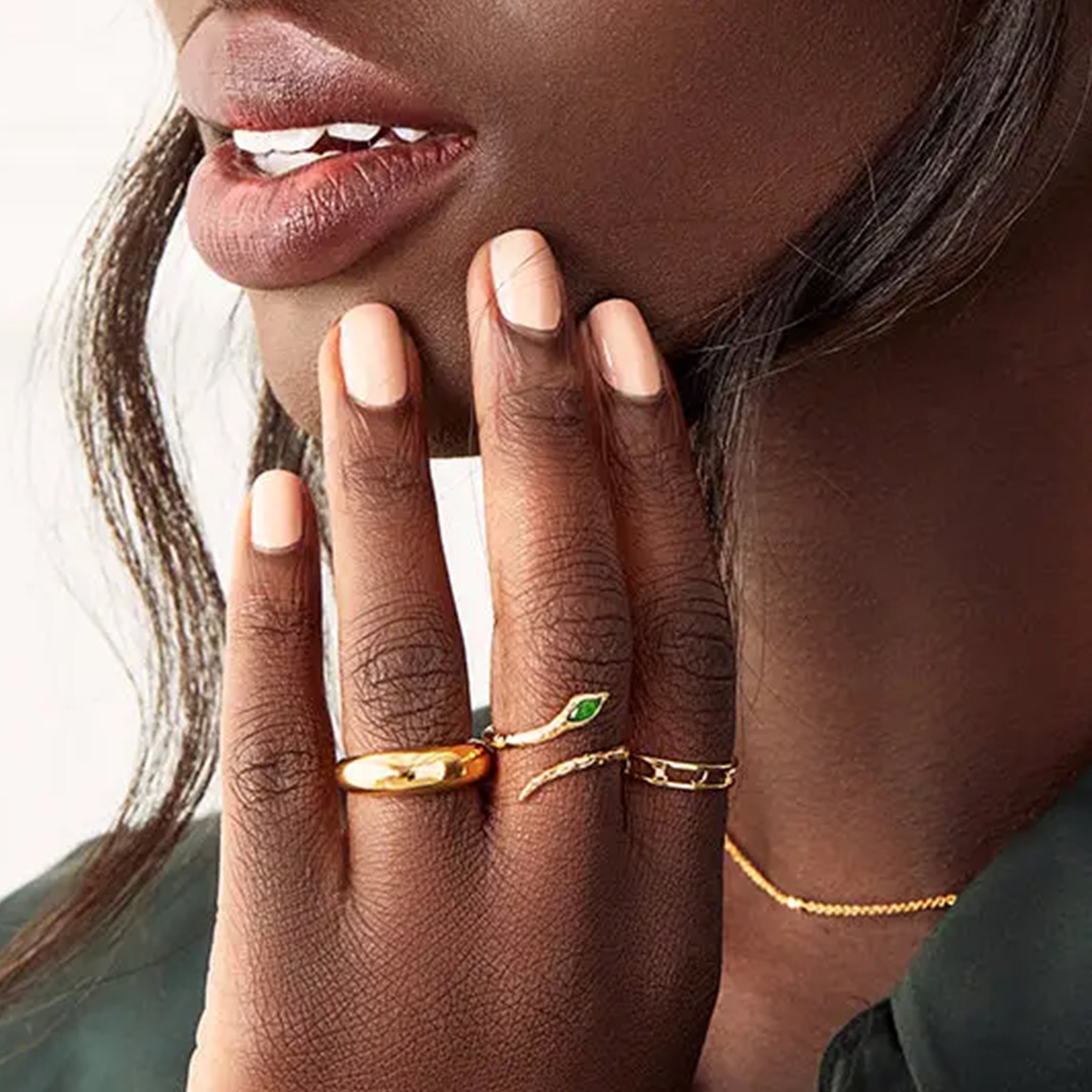 A gold snake shaped ring with a green quartz stone where the head of the snake is. 