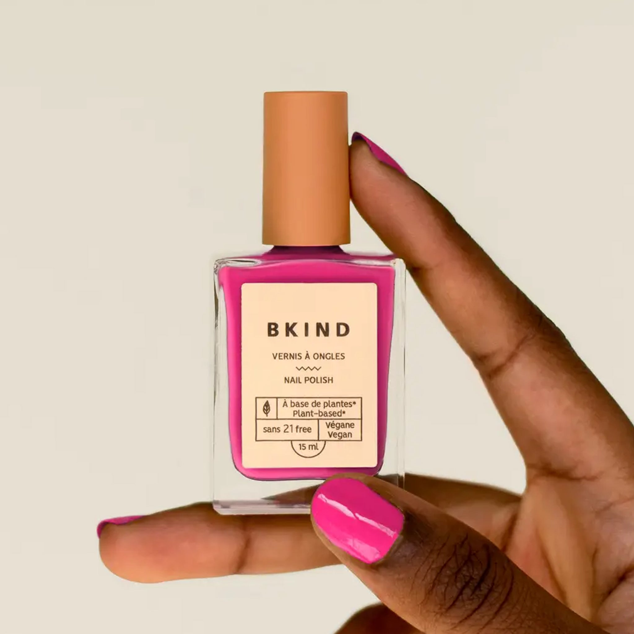 A bright fuchsia shade of nail polish in a rectangle bottle. 