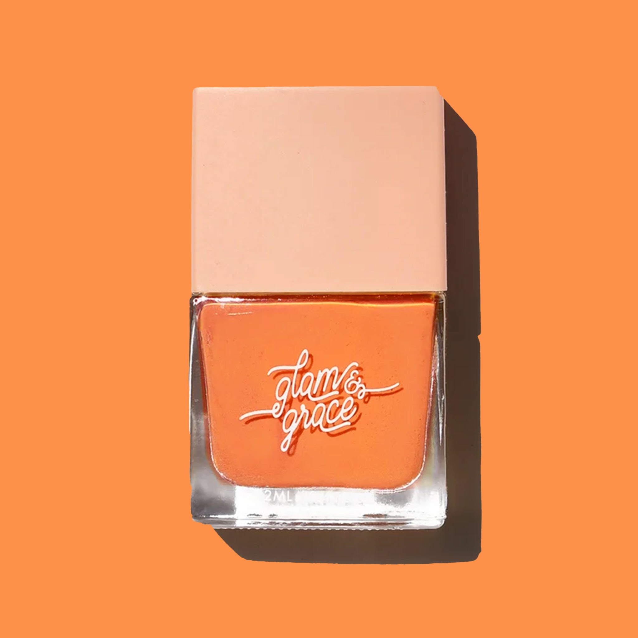 On an orange background is a square bottle of orange nail polish. 