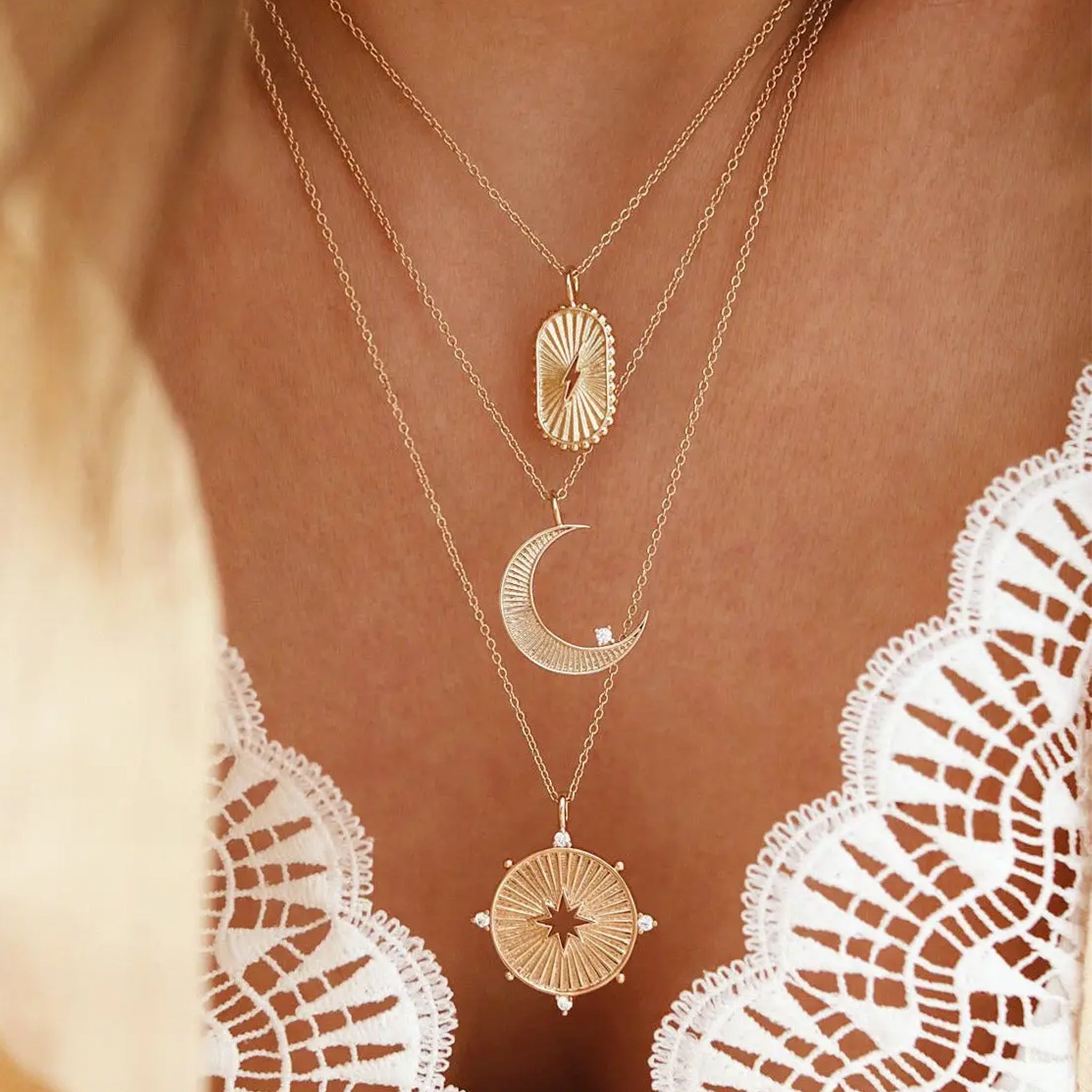 A gold necklace with a moon shaped pendant and a cz stone on the edge. 