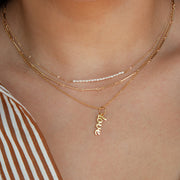 A gold chain necklace with a pendant that reads, 'love'. 