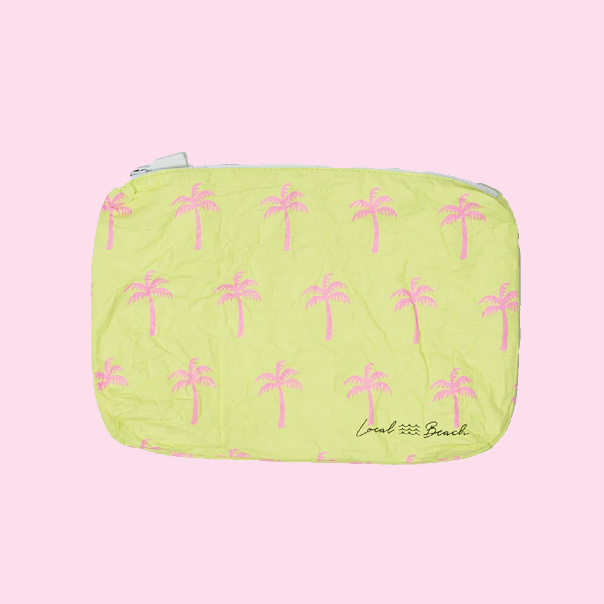On a light pink background is a yellow pouch with a pink palm tree pattern. 