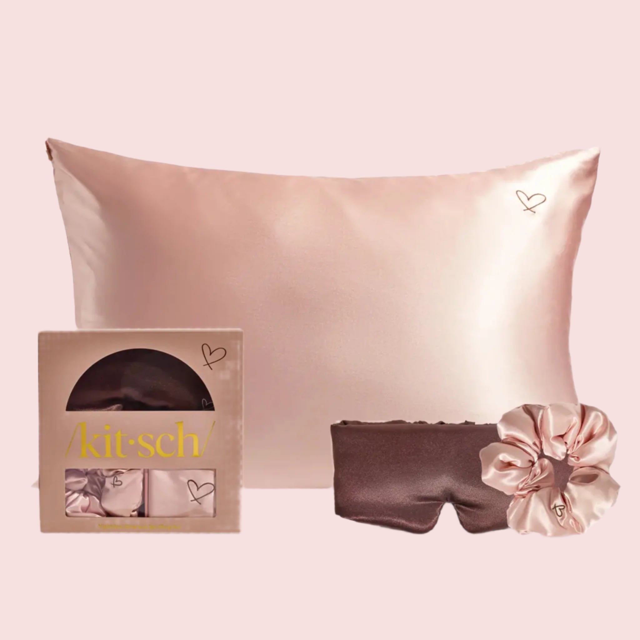 A three piece set that includes on light pink satin pillow case, one brown sleep mask and one light pink scrunchie. 