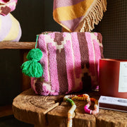 The medium nisha terry pouch in pink with a green tassel zipper. 