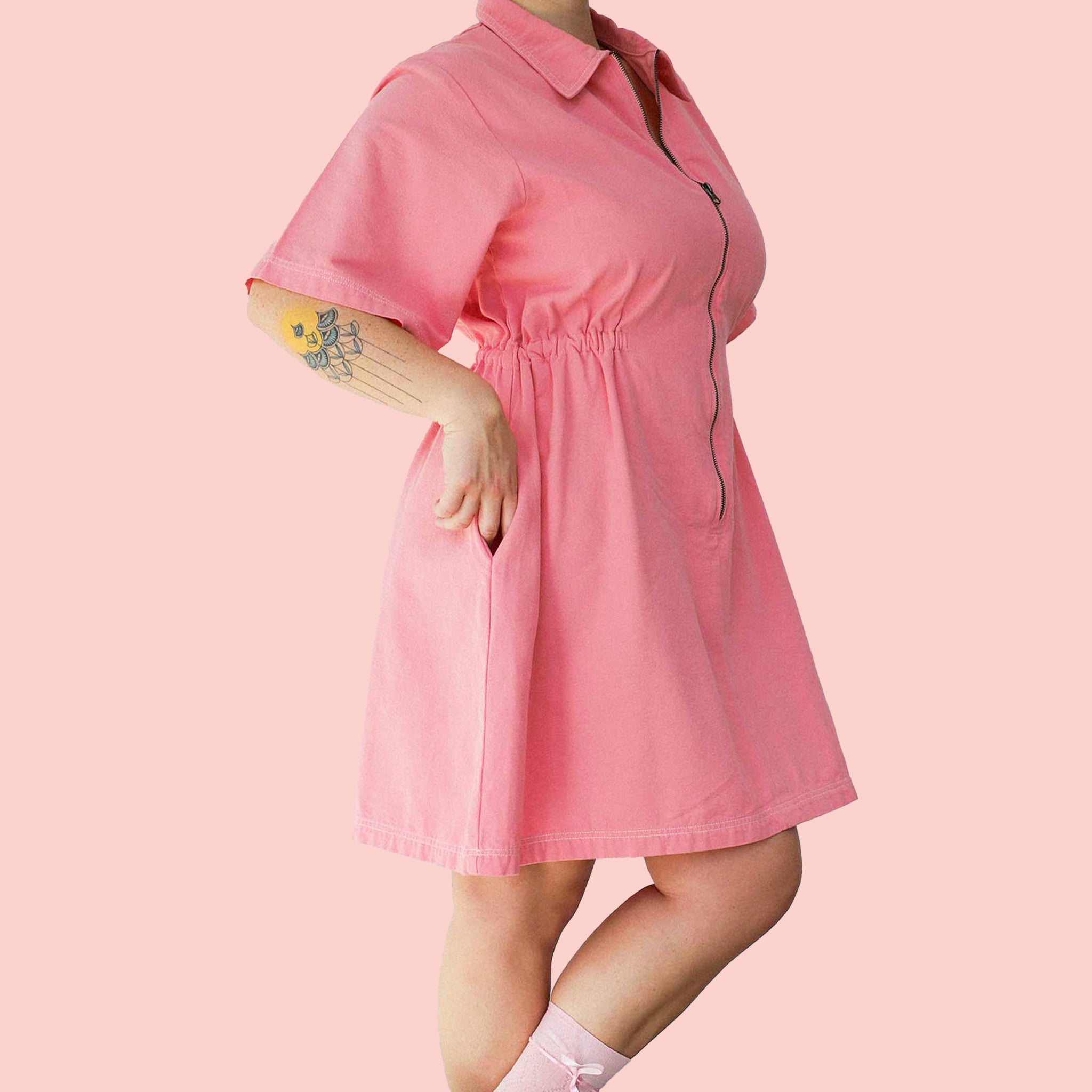 A short pink utility dress with a front zip and pockets.