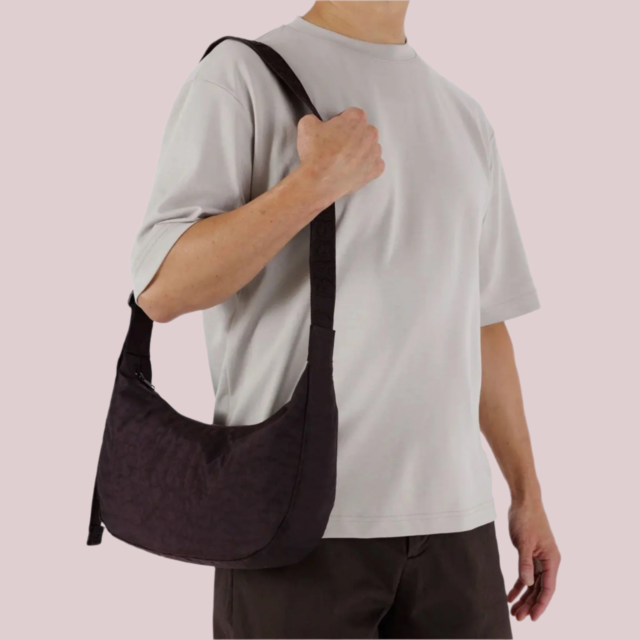 A purple/brownish colored nylon crescent bag with a black strap and details. 