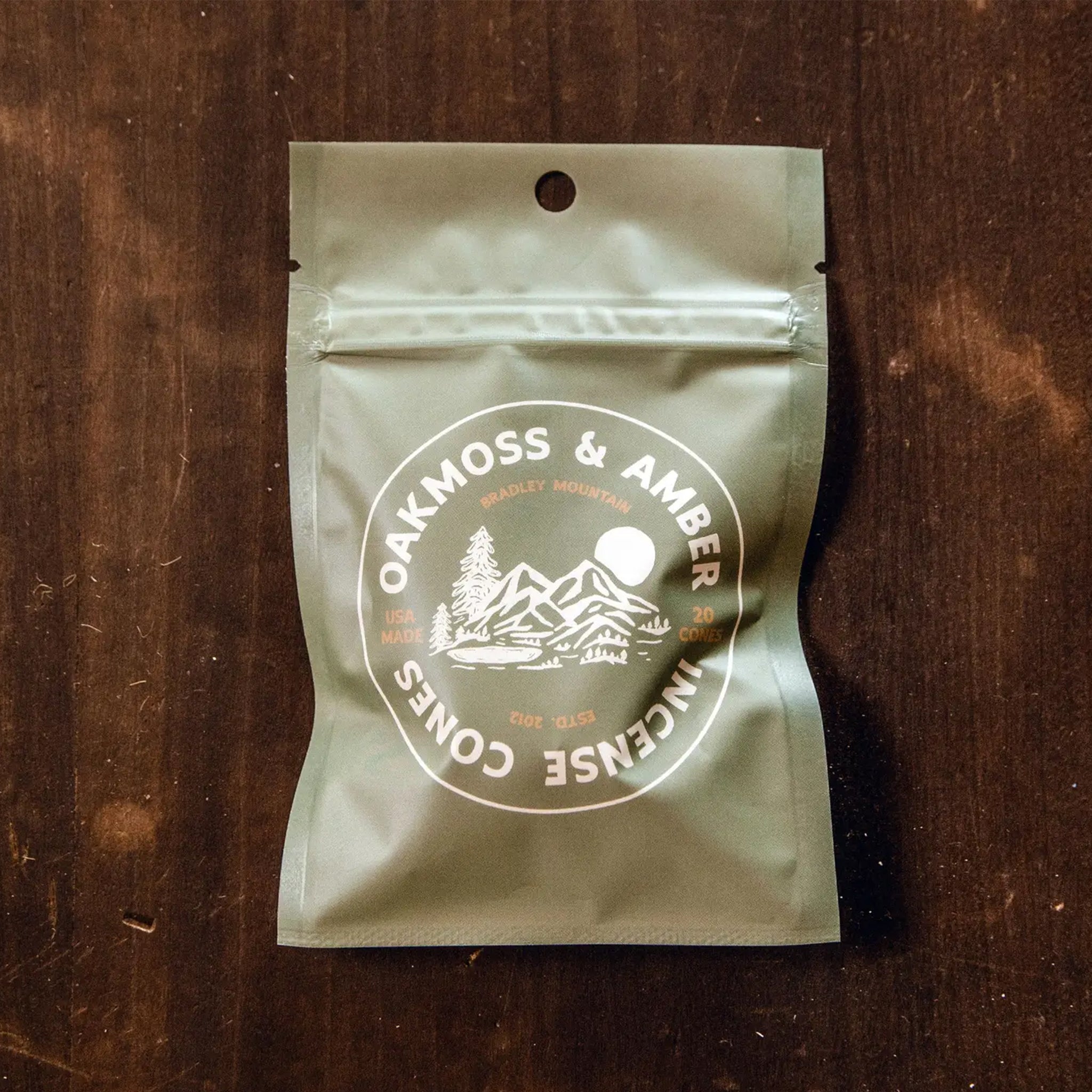 A bag of 20 incense cones in a neutral packaging with text that reads, 'Oakmoss & Amber Incense Cones'. 