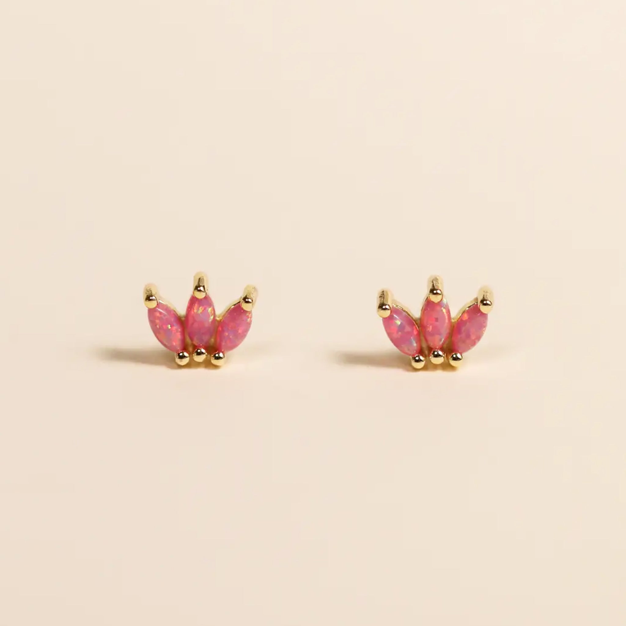 A pair of pink crown shaped stud earrings made of pink opal stones. 