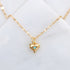 A gold chain necklace with a small gold heart shaped pendant with a blue opal in the center. 