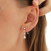 A pair of earrings with three cz stones and a teardrop shaped opal stone. 