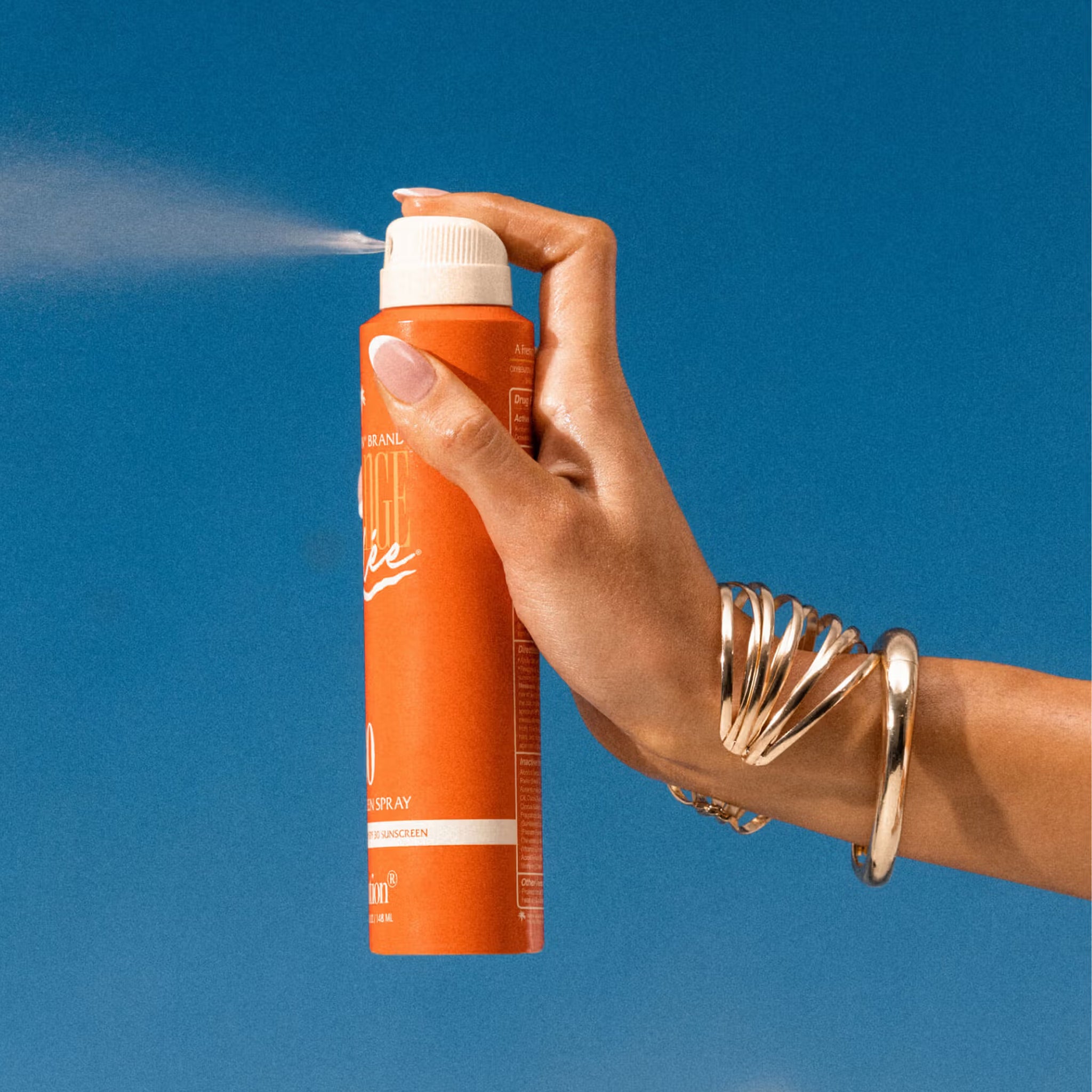 An orange spray bottle of product with text on the front hat reads, 'Vacation Orange Gelee'. 