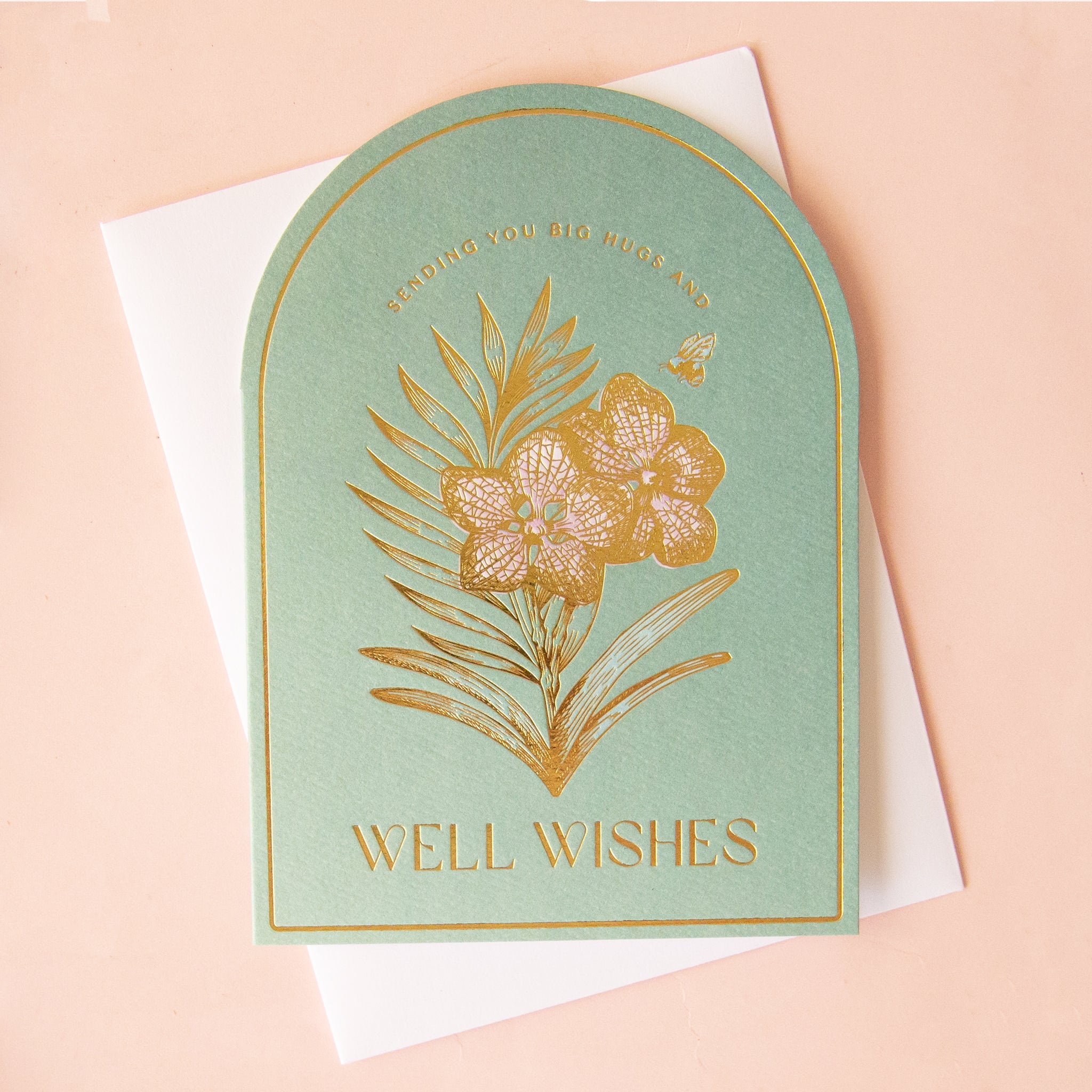 On a tan background is a light green card with an orchid in gold foil and text above and below that reads, "Sending you big hugs and well wishes".