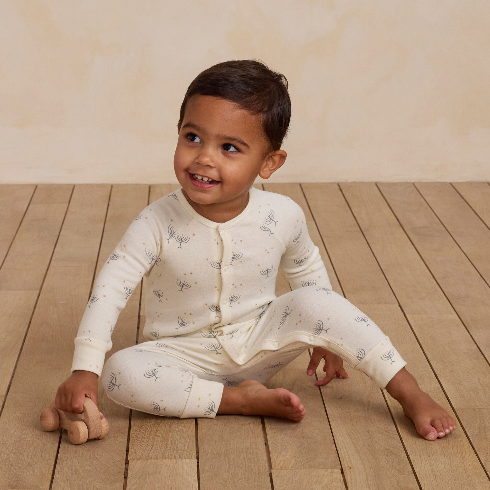 A cream colored long john pajamas with a menorah Hanukkah print. 