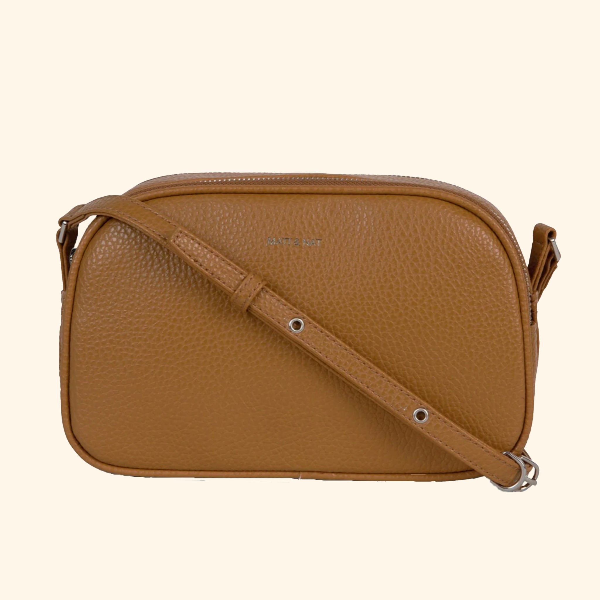 A brown crossbody bag with an adjustable strap and two zipper openings. 