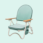 A green arched folding beach chair with wood arm rests and a zipper pocket in the back.