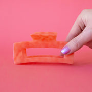 A coral rectangle shaped claw clip. 