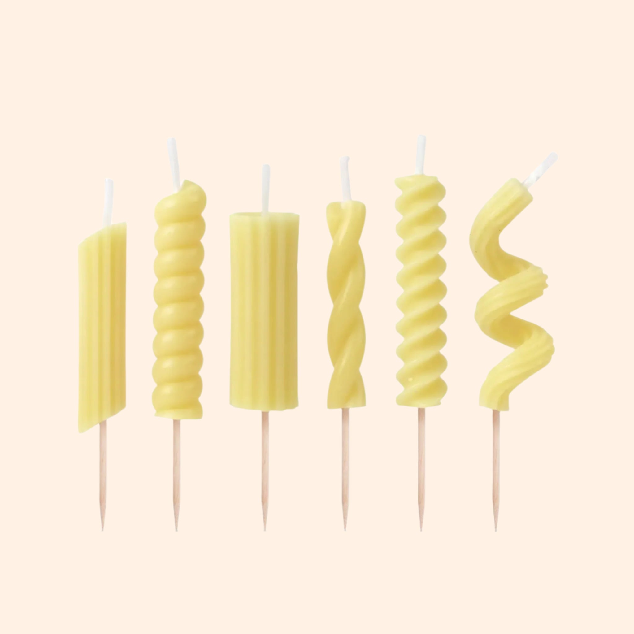 A variety of six different types of pasta shaped birthday candles with toothpicks at the bottom.