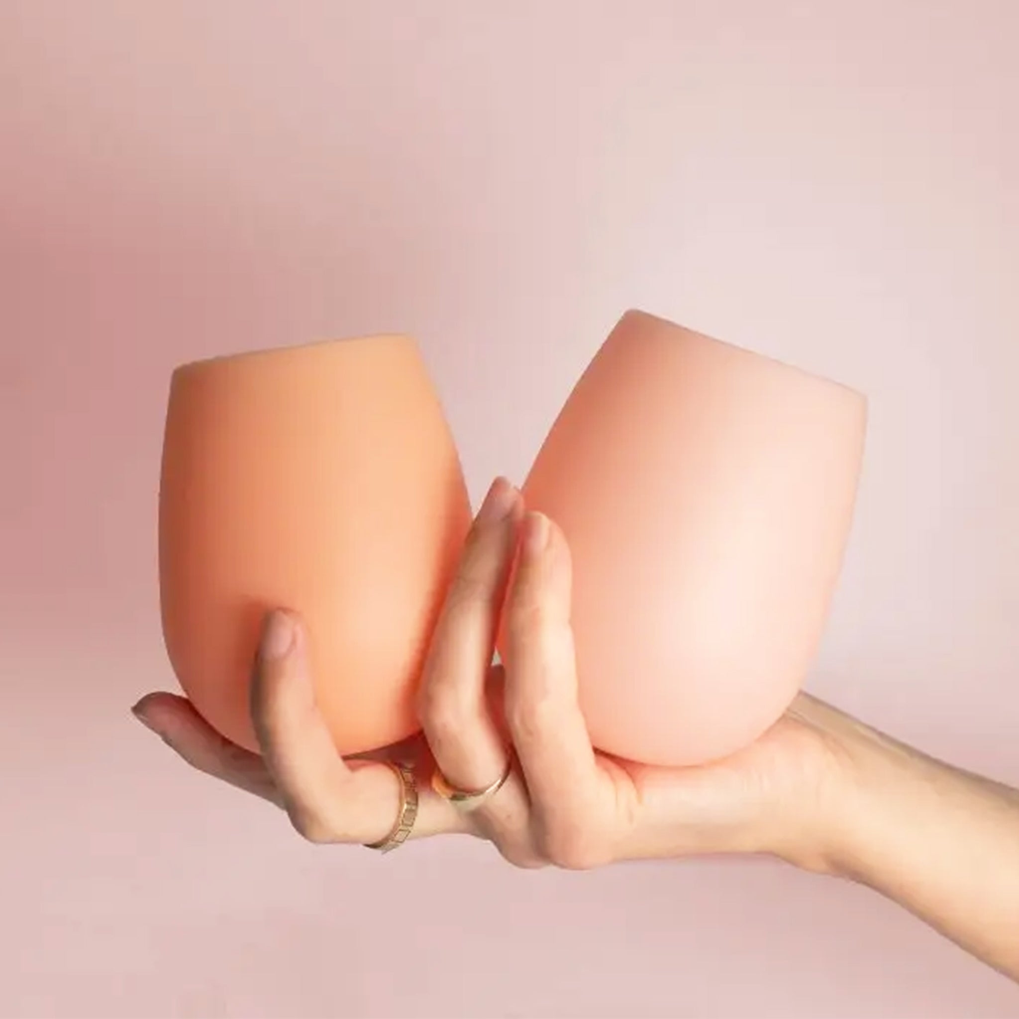 Two peach and pink colored silicone stemless cups. 