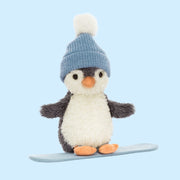 A penguin shaped stuffed animal wearing a beanie and standing on a snowboard. 