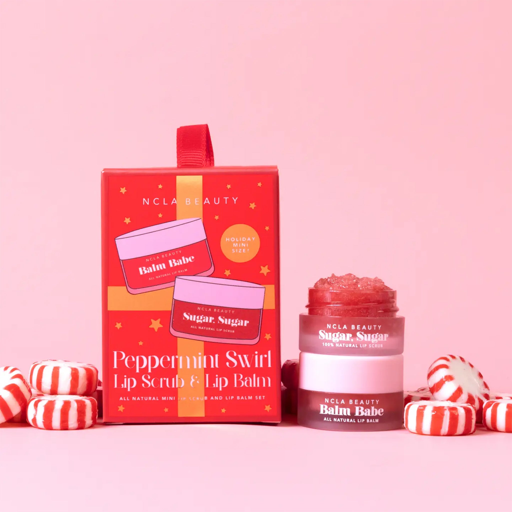 A set of one lip scrub and lip balm in a red package that is also a loop for hanging on a tree. 