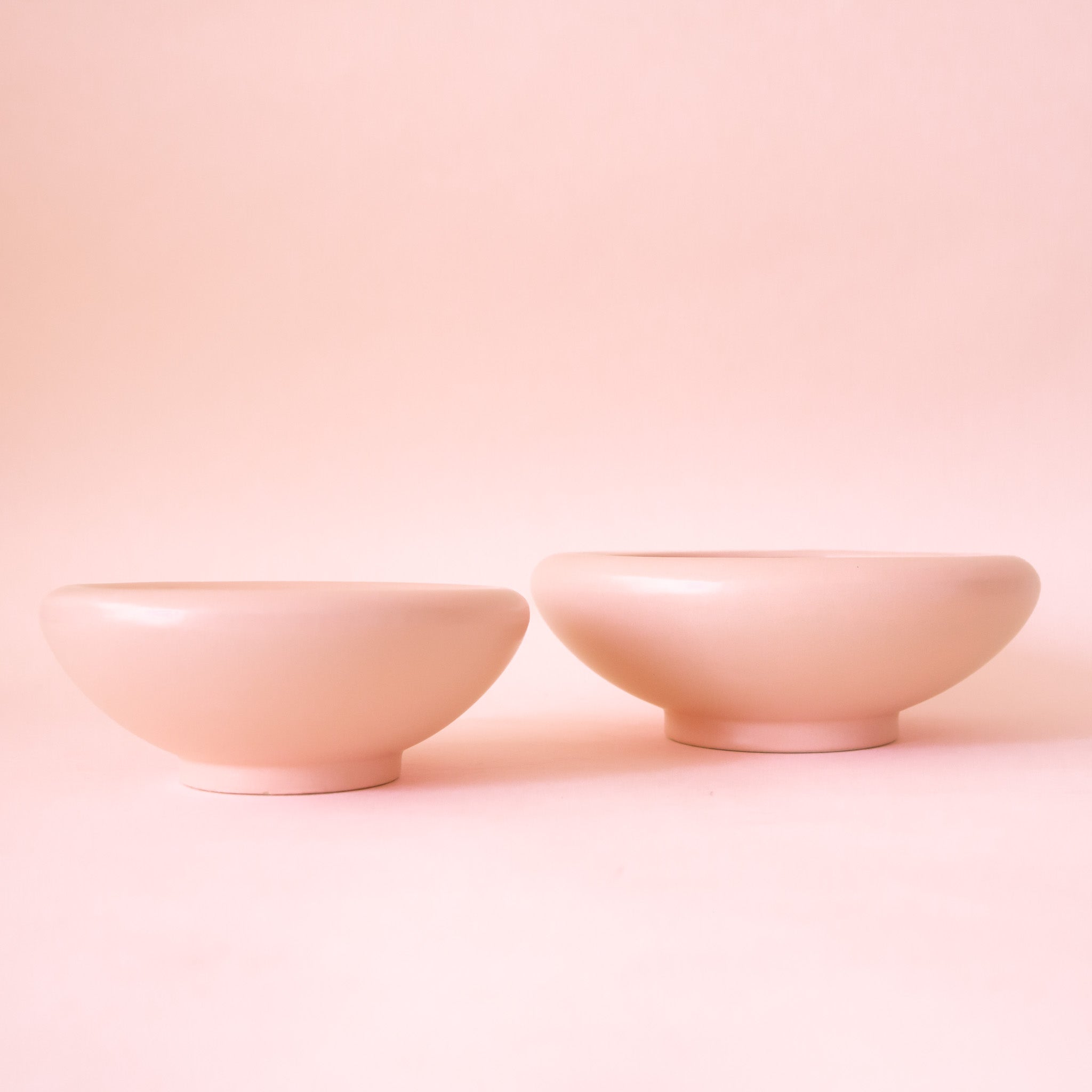 A light pink ceramic low bowl planter with a rounded edge in two different sizes. 