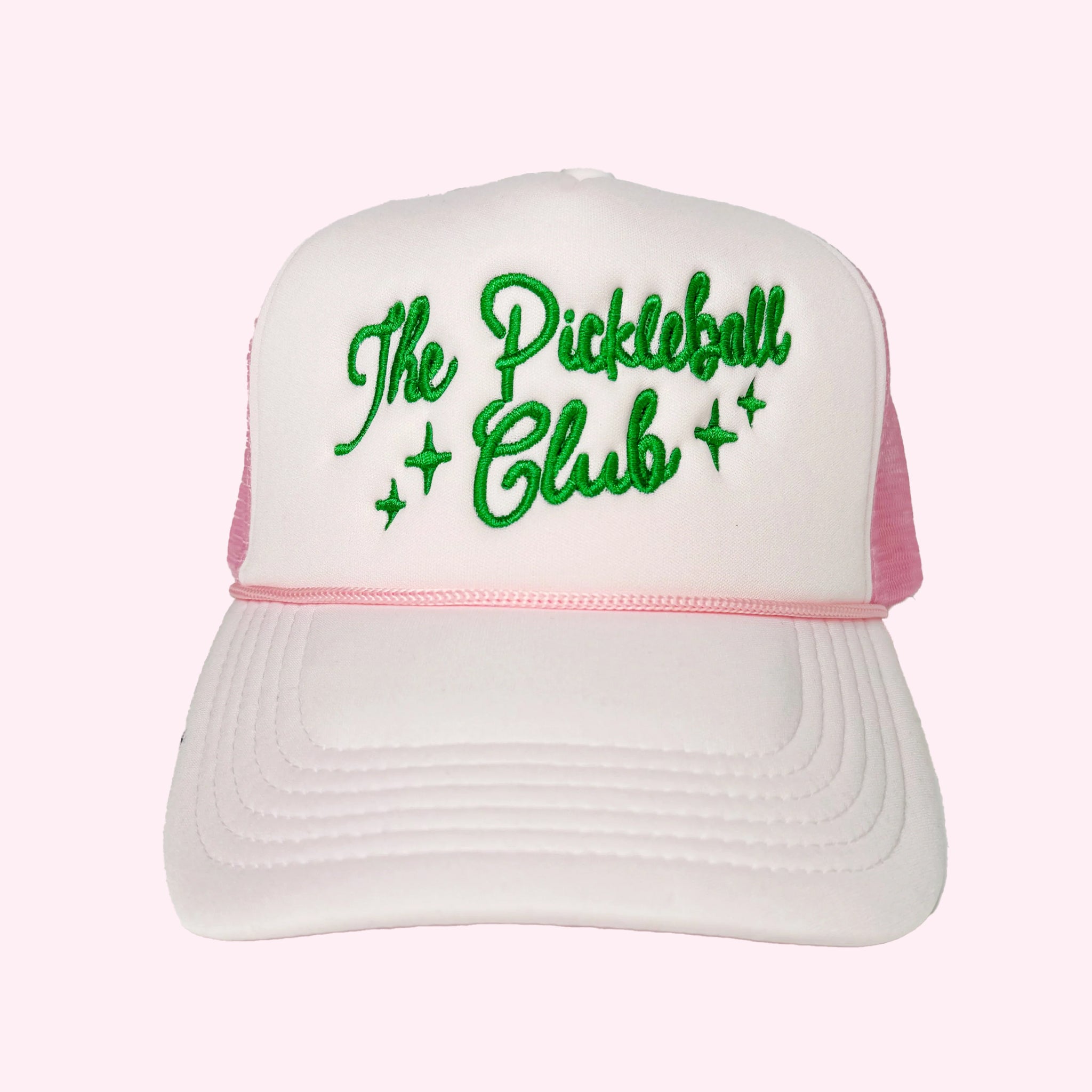 A light pink trucker hat with green embroidered text across the front that reads, &quot;The Pickleball Club&quot;. 