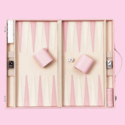 On a pink background is a pink and tan backgammon board game set. 
