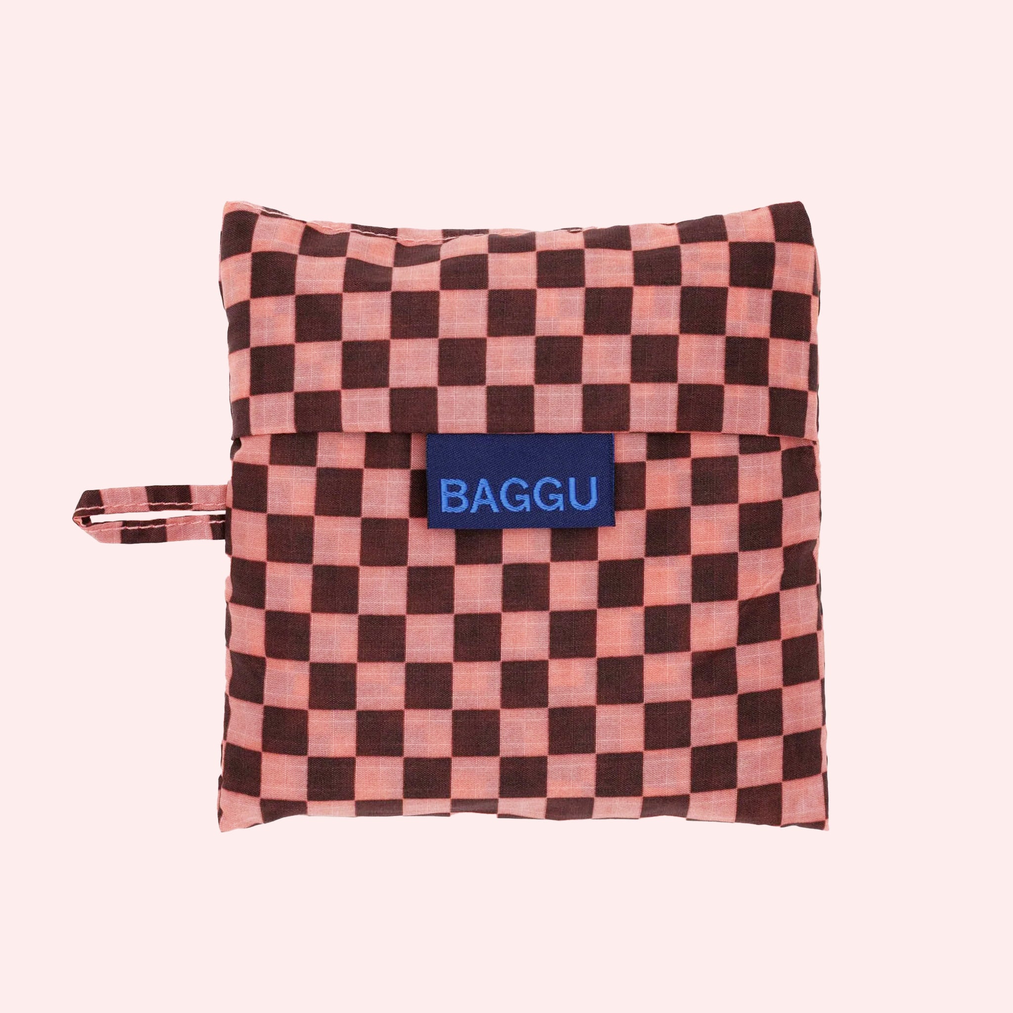 A pink and brown checker print nylon tote bag that has the option to be folded into a compact square for on the go. 