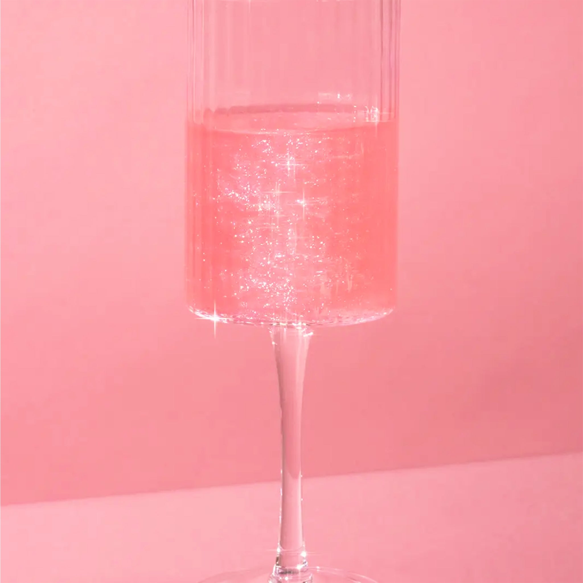 A champagne glass with a beverage inside that displays the glitter shimmer bomb's effect to the liquid. 