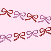 A pink and red glitter bow garland made out of paper cut outs. 