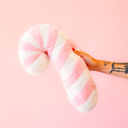 A light pink and white striped candy cane shaped pillow. 