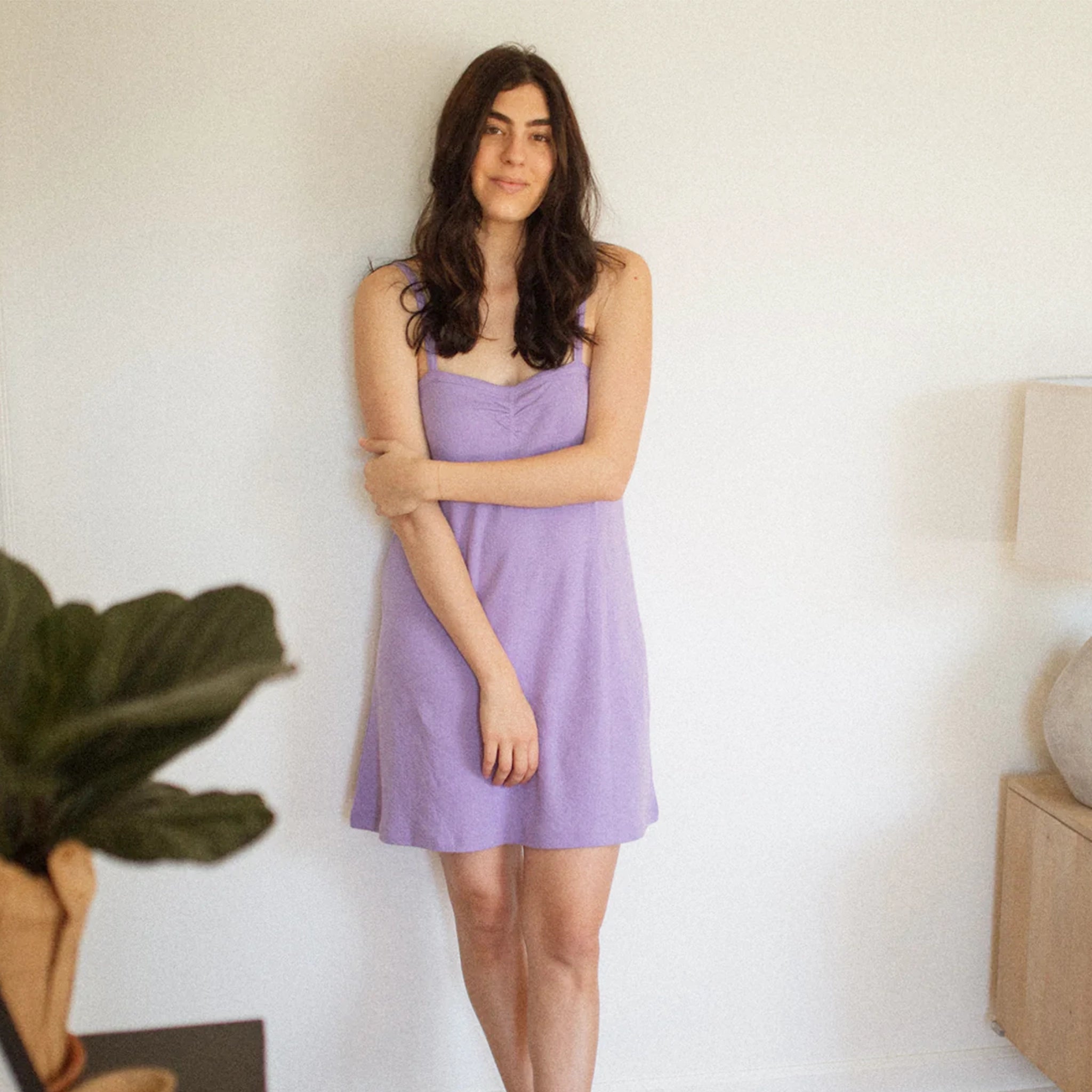 On a white background is a model wearing a lavender pointelle dress. 