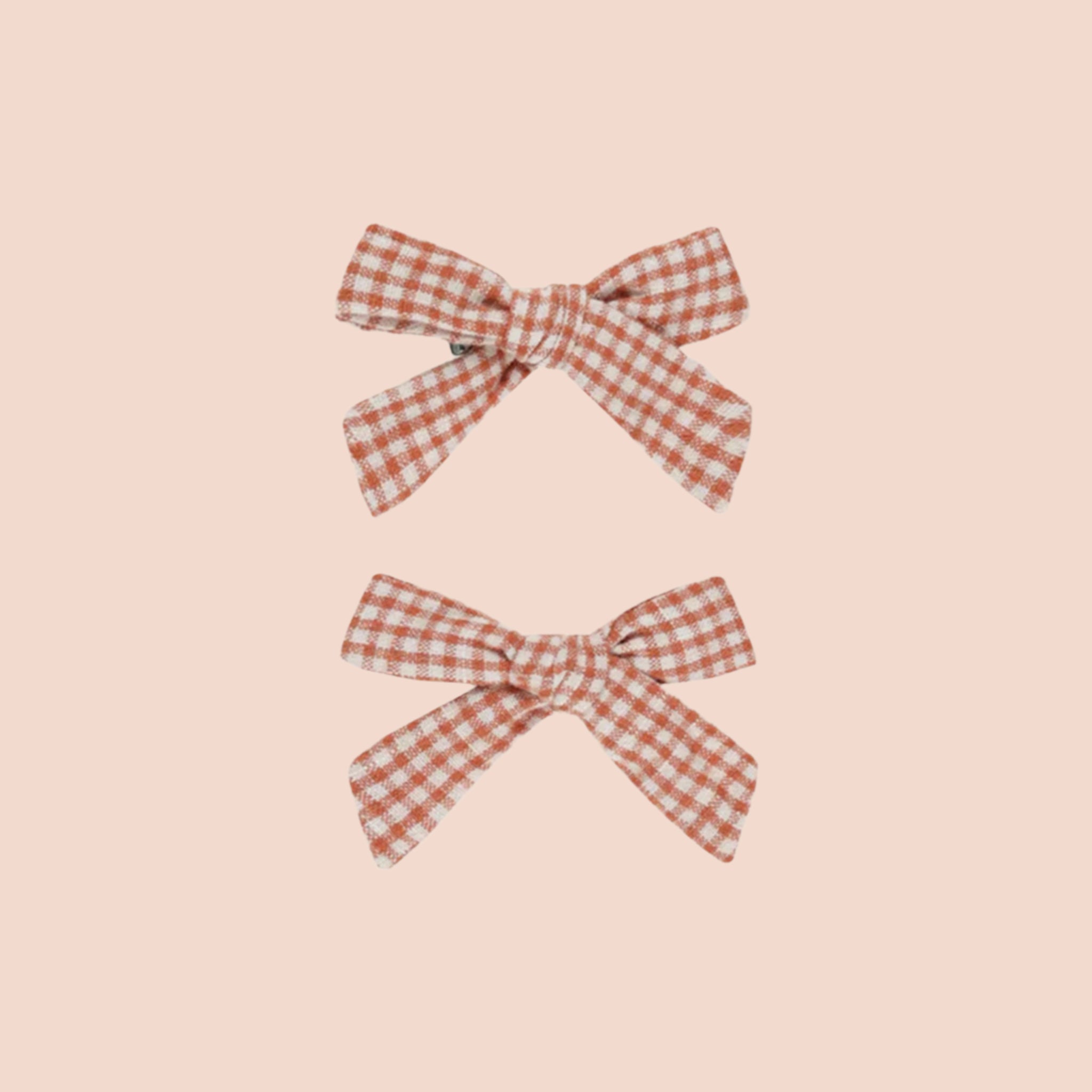 A pair of red and cream gingham printed bows for children. 