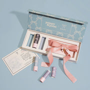 A gift box filled with three lip balms and a pink bow. 