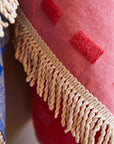 A pink bath towel with a floral print and fringe details on two edges. 