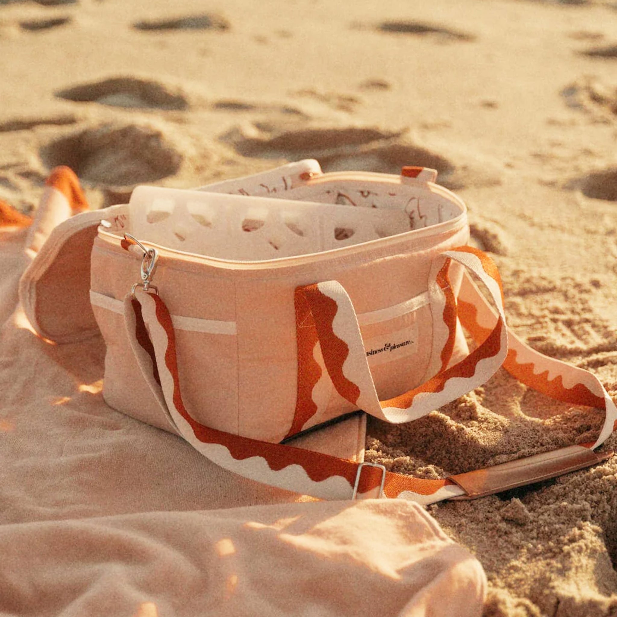 A pink and red premium cooler bag with leather handle straps.