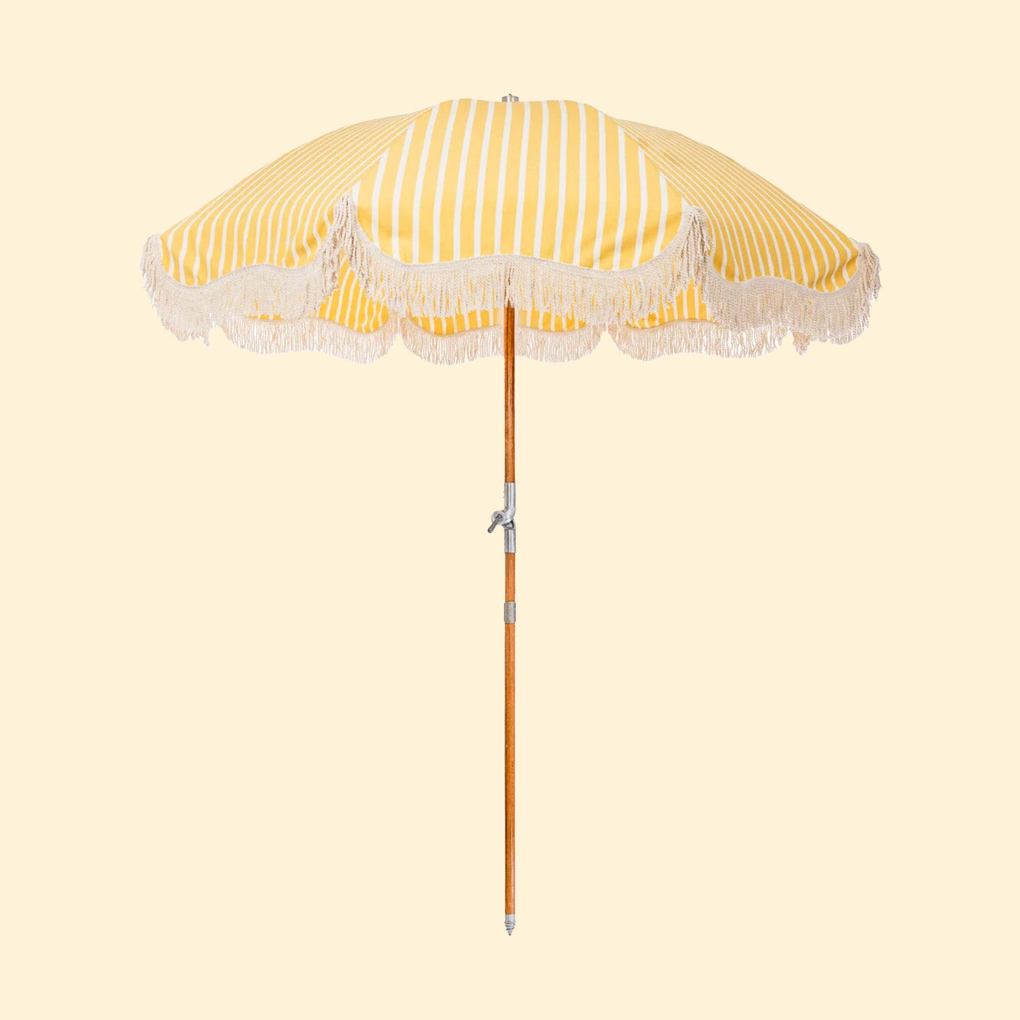 A white and yellow striped outdoor umbrella with a rope fringe detail around the edge.