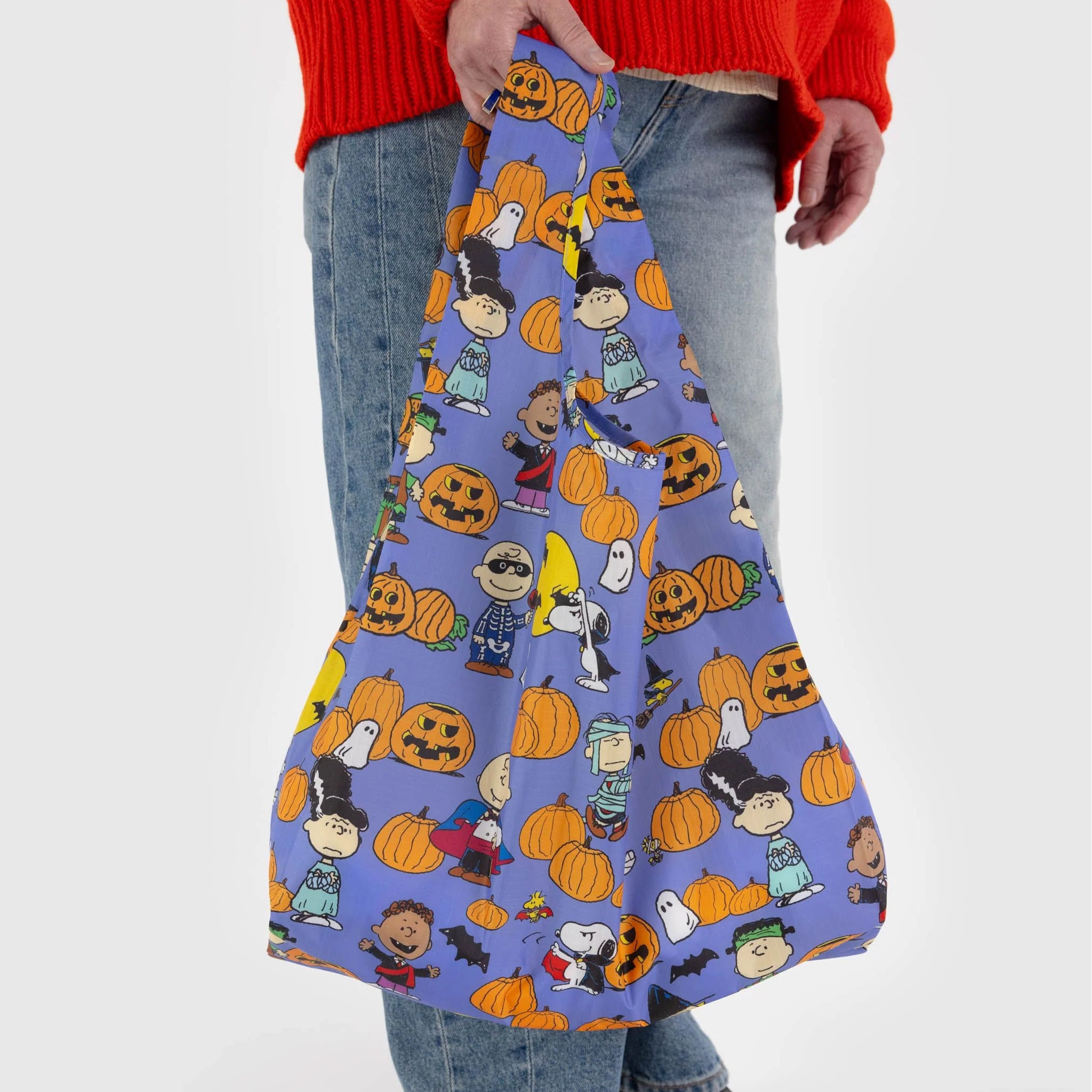 A purple reusable nylon bag with a charlie brown pumpkin patch pattern all over.