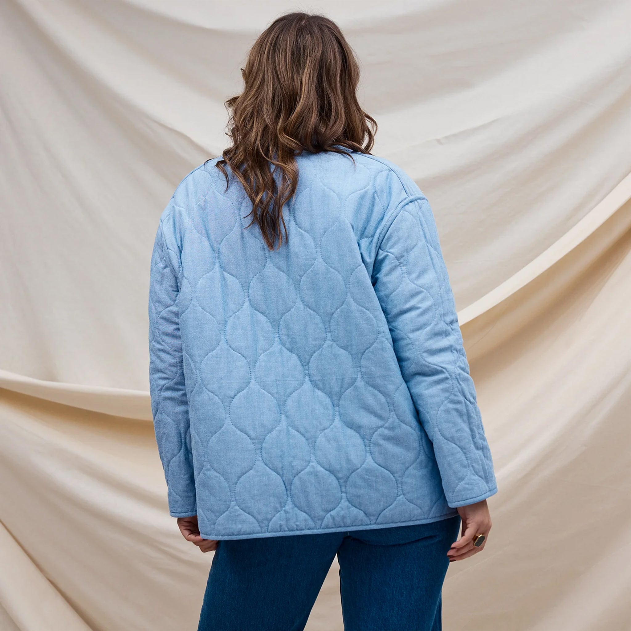 A multi colored quilted jacket with a floral print on one side and a blue solid color on the other. 