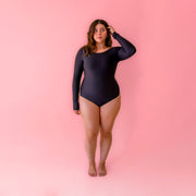 A black one piece, long sleeve swim suit with cut outs on the hips. 